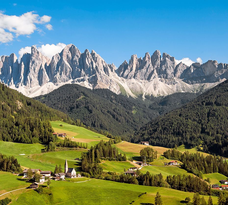 Panoramic view of Geisler peaks Dolomites with St. Magdalena village Villnoss and green alpine meadows