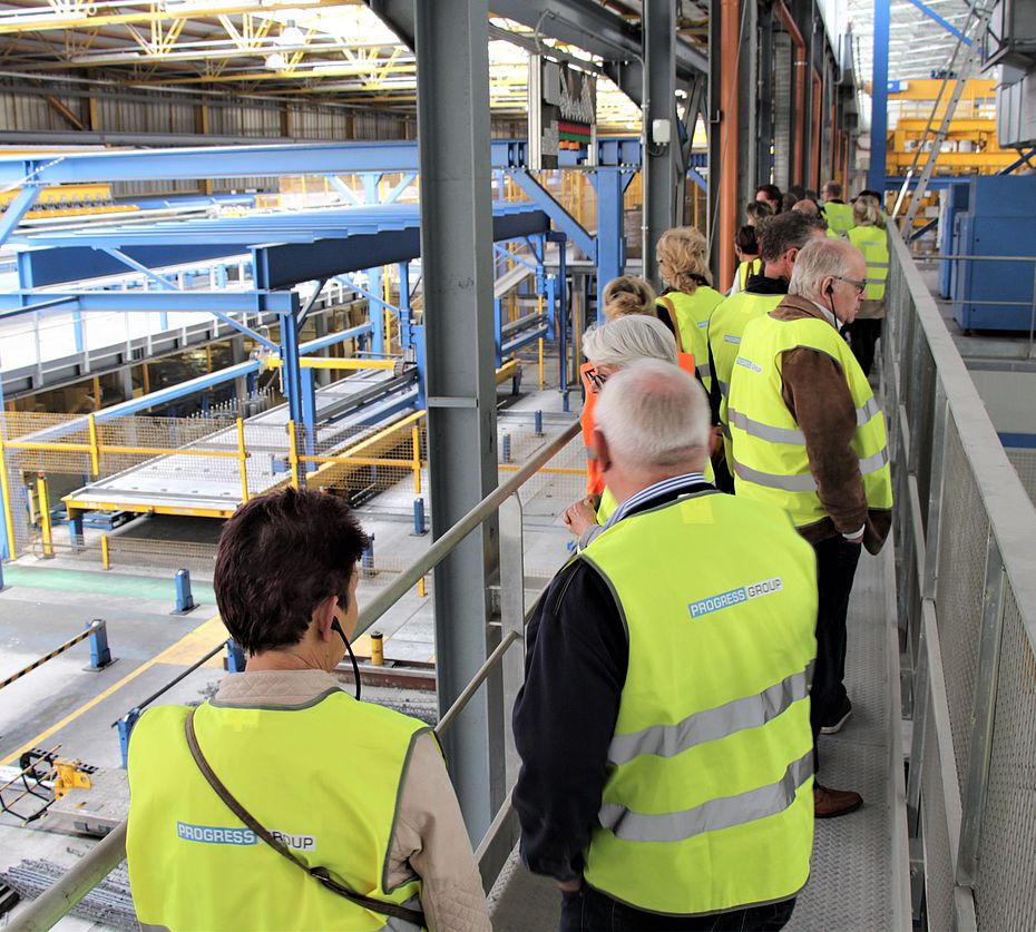 Visitor group with safety vests tours Progress Group industrial precast concrete production plant